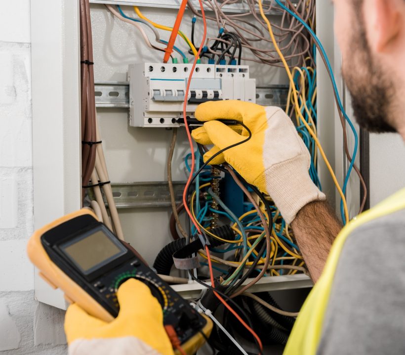 cropped-image-of-electrician-checking-electrical-box-with-multimetr-in-corridor